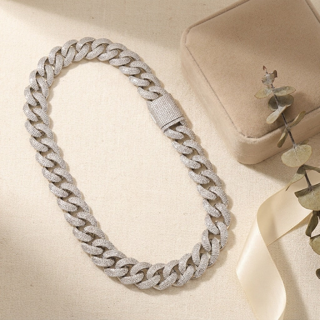 20 mm iced out Cuban link chain laid flat beside a gift box and a eucalyptus sprig